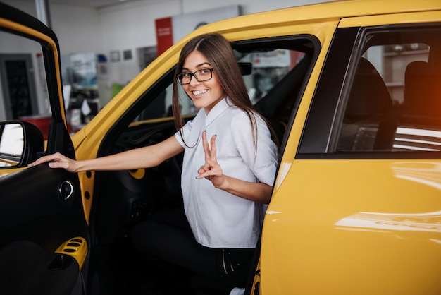 Junge Frau in ihrem neuen Auto lächelnd