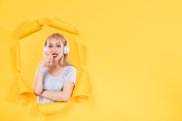 Junge Frau in Kopfhörern auf gelbem Hintergrund Audio-Ultraschallmusik