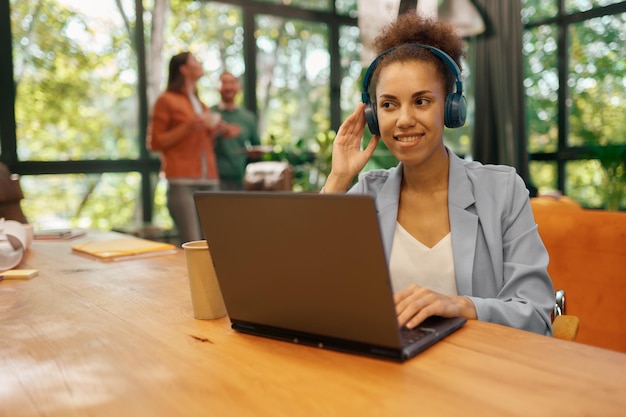 Junge Frau in Kopfhörern mit Laptop für Online-Arbeit