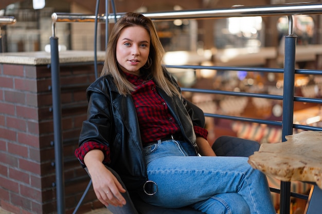 Foto junge frau in lederjacke auf einem stuhl