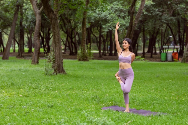 junge Frau in lila Sportkleidung beim Yoga im Freien