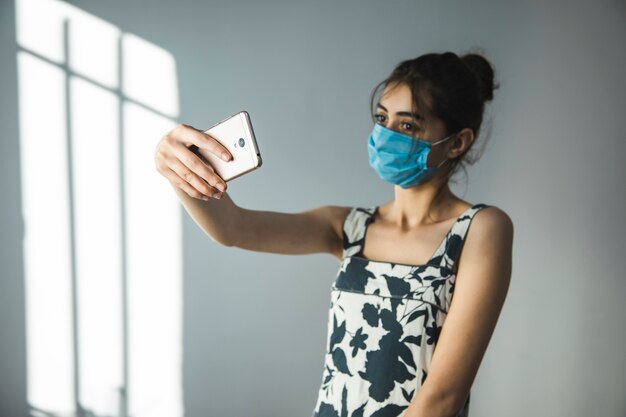 Junge Frau in Maske machen Selfie