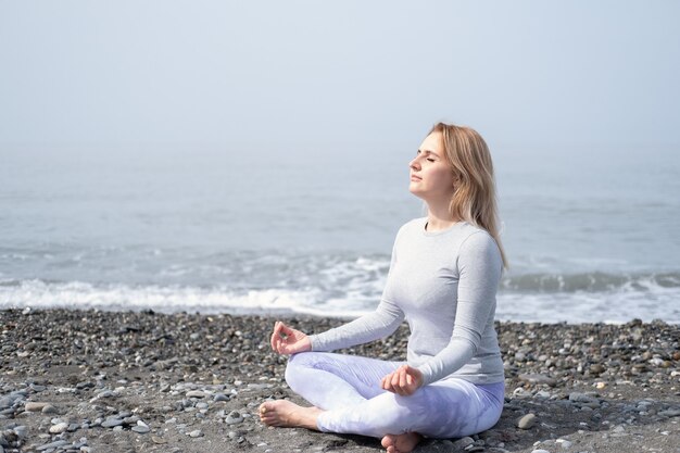 Junge Frau in Meditationshaltung am Strand