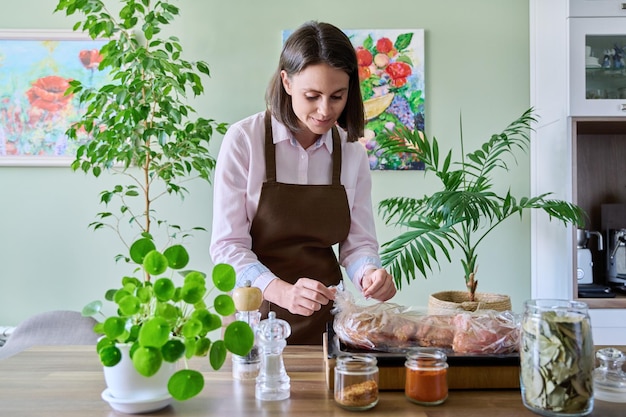 Junge Frau in Schürze, die zu Hause Fleisch in der Brathülsenküche kocht