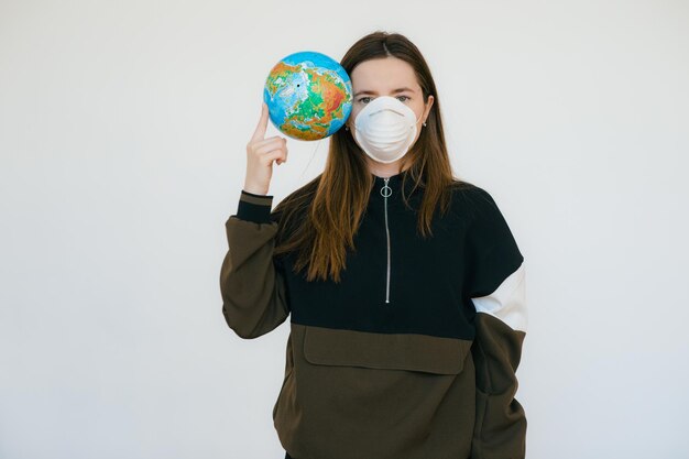 Junge Frau in schützender Gesichtsmaske mit Globus