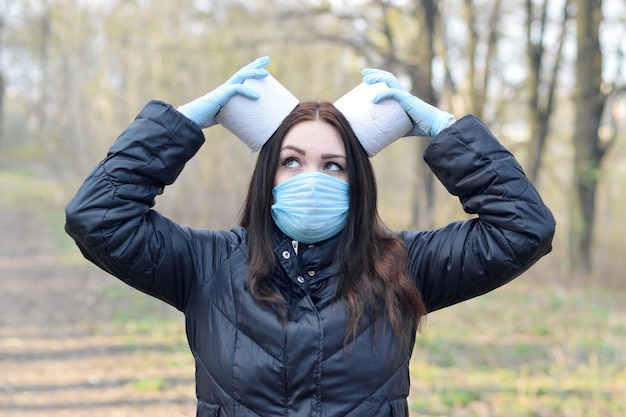 Foto junge frau in schutzmaske hält rollen toilettenpapier