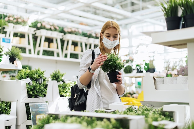 Junge Frau in Schutzmaske kauft Blumen in einem Gartencenter.