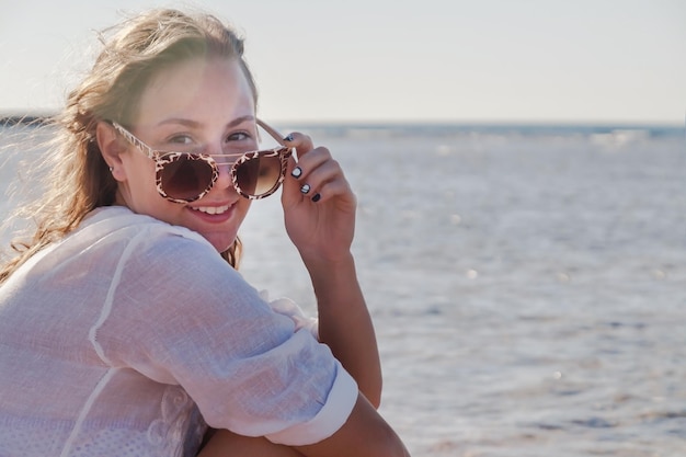 Junge Frau in Sonnenbrille mit sich entwickelndem Haar lächelnd Konzept der Sommerruhe der Jugend