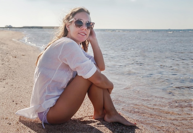 Junge Frau in Sonnenbrille mit sich entwickelndem Haar lächelnd Konzept