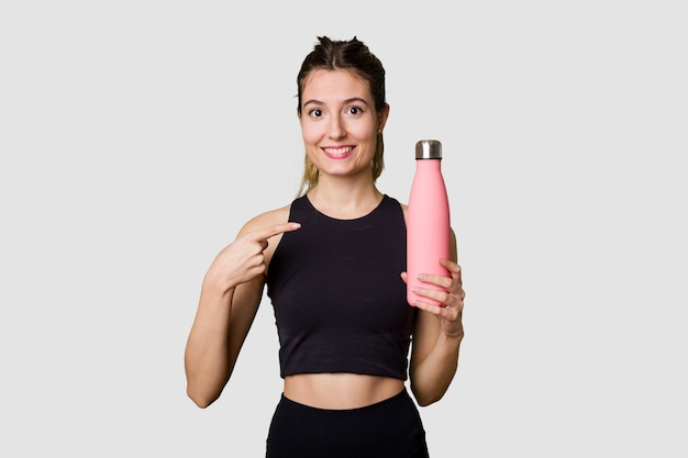 Junge Frau in Sportbekleidung hält eine Wasserthermoskanne bereit für ihren aktiven Lebensstil