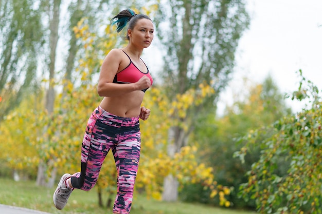 junge Frau in Sportbekleidung läuft im Park