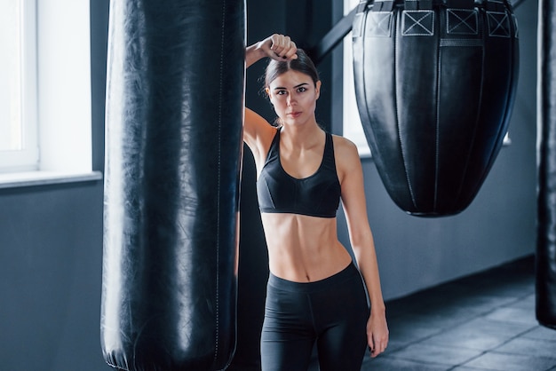 Junge Frau in sportlicher Kleidung ist in der Turnhalle und hat einen Trainingstag. Konzeption des Boxens.