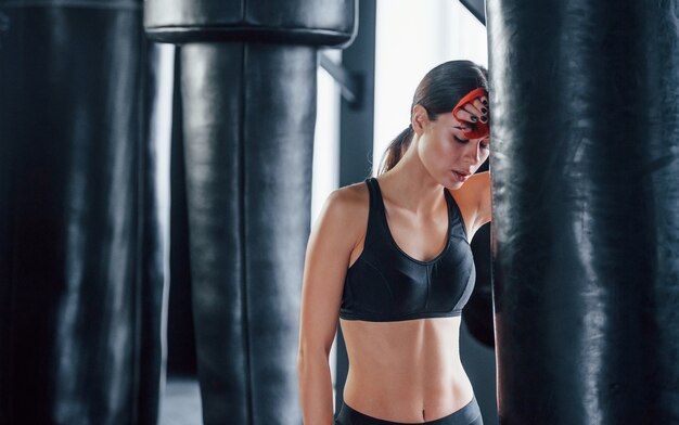 Junge Frau in sportlicher Kleidung ist in der Turnhalle und hat einen Trainingstag. Konzeption des Boxens.