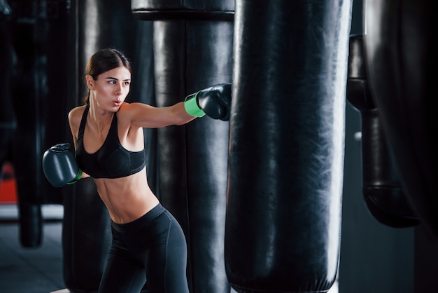 Junge Frau in sportlicher Kleidung ist in der Turnhalle und hat einen Trainingstag. Konzeption des Boxens.