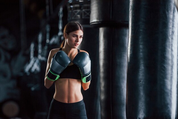 Junge Frau in sportlicher Kleidung ist in der Turnhalle und hat einen Trainingstag. Konzeption des Boxens.