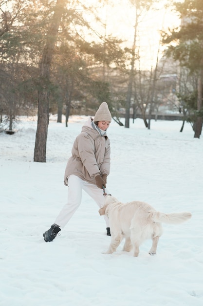 Junge Frau in warmer Kleidung, die draußen zusammen mit ihrem Hund geht