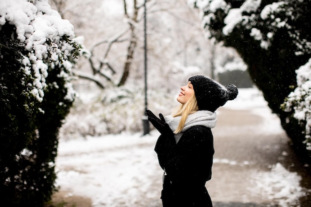 Junge Frau in warmer Kleidung, die im Schnee genießt