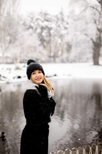 Junge Frau in warmer Kleidung, die im Schnee genießt