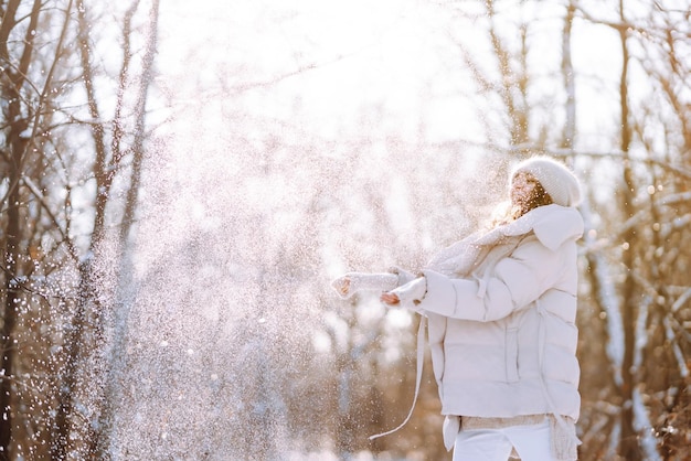 Junge Frau in Winterkleidung, die im verschneiten Park spazieren geht Wintermodeurlaub