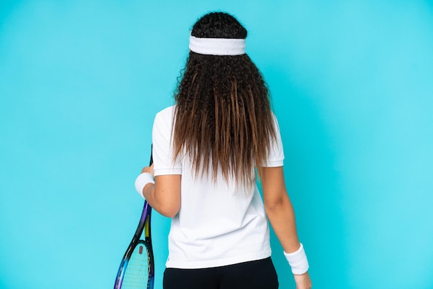 Junge Frau isoliert auf blauem Hintergrund beim Tennisspielen