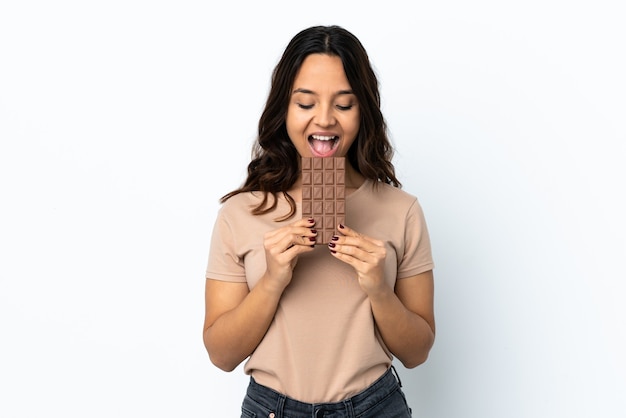 Foto junge frau isoliert, die eine schokoladentafel isst