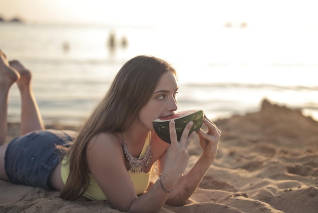 junge Frau isst eine Wassermelone am Strand