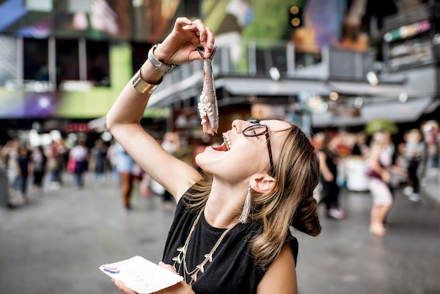 Junge Frau isst Hering mit Zwiebeln traditioneller holländischer Snack auf dem Rotterdamer Markt