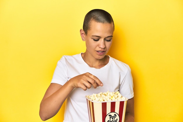 Junge Frau isst Popcorn Kino-Konzept gelbe Hintergrund