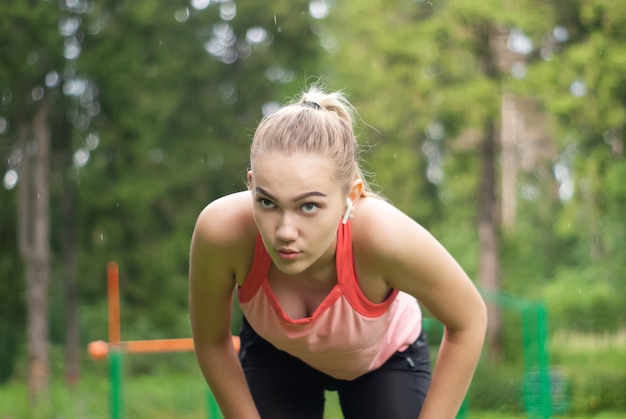 Junge Frau ist außer Atem und macht eine Verschnaufpause beim Sport im Freien