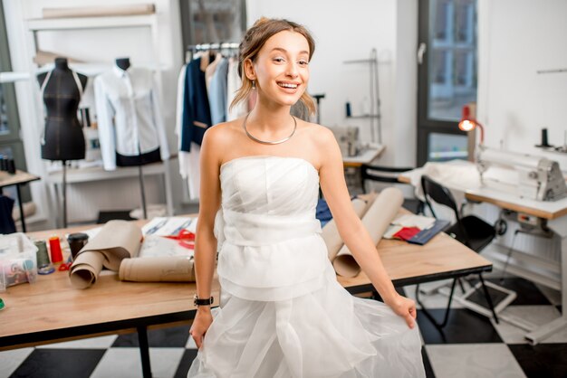 Junge Frau Klientin passendes Hochzeitskleid, das im Schneideratelier steht