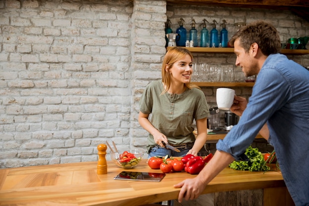 Junge Frau kocht, während Mann Kaffee trinkt