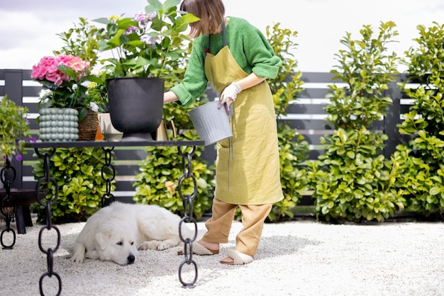 Junge Frau kümmert sich um Blumen mit Hund im Garten