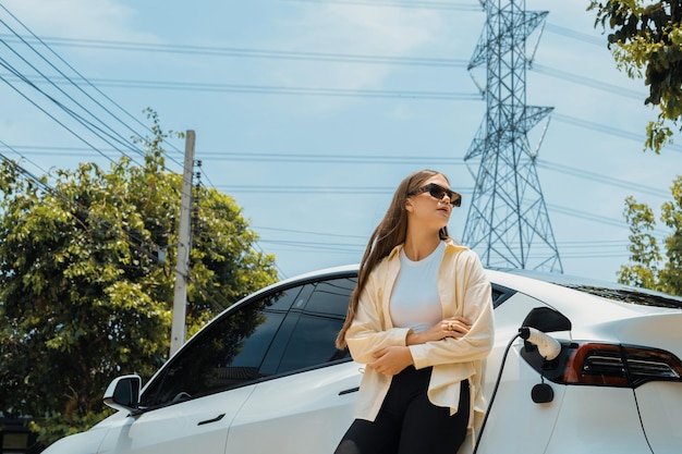 Junge Frau laden die Batterie eines E-Autos an einer Ladestation auf