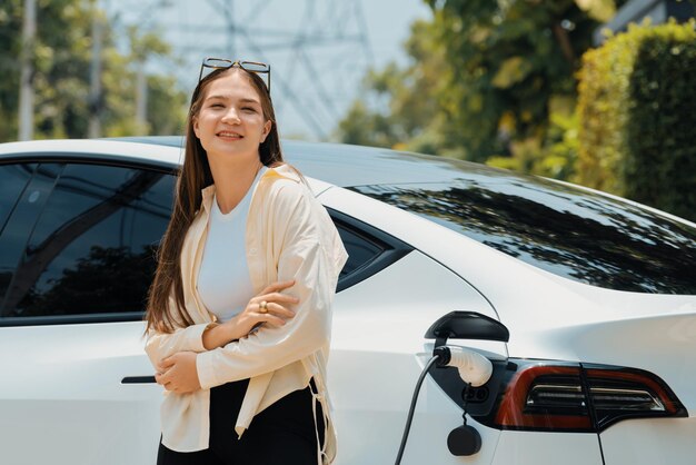 Junge Frau laden ihr EV-Elektrofahrzeug im Green City Park auf