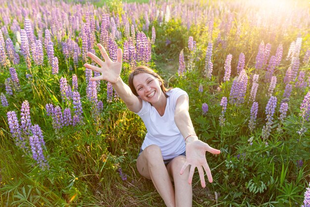 Junge Frau lächelt im Freien schönes Brunete-Mädchen, das auf Sommerfeld mit blühenden wilden Blumen ruht