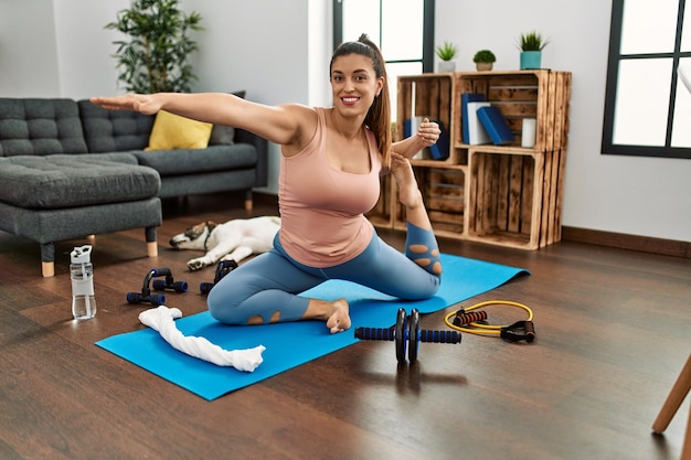 Junge Frau lächelt zuversichtlich, Yoga zu Hause zu trainieren