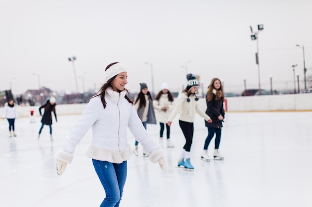 Junge Frau läuft tagsüber Schlittschuh auf der Eisbahn