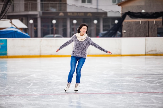 Junge Frau läuft tagsüber Schlittschuh auf der Eisbahn