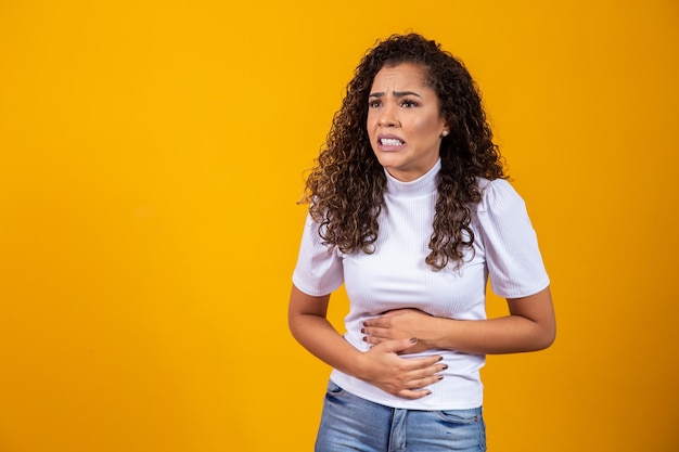 Junge Frau leidet unter Bauchschmerzen. Menstruationskrämpfe, Durchfall, Bauchschmerzen, Konzept der frühen Schwangerschaft