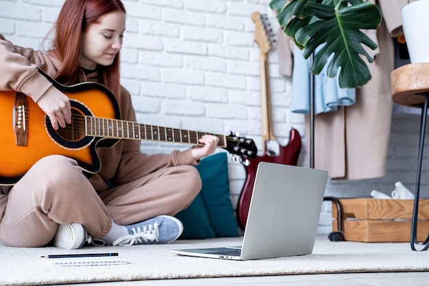 Junge Frau lernt zu Hause Gitarre zu spielen