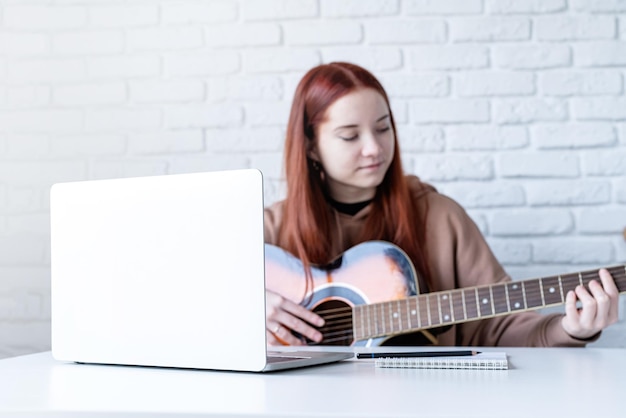 Junge Frau lernt zu Hause Gitarre zu spielen