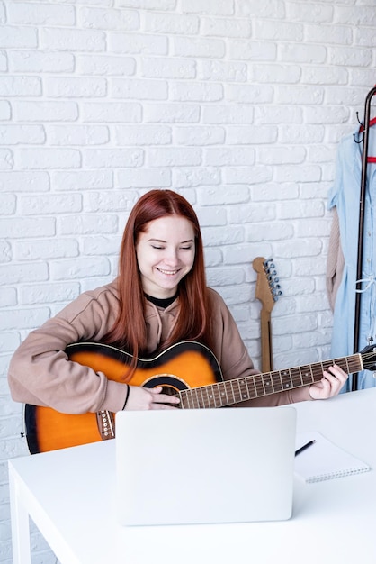 Junge Frau lernt zu Hause Gitarre zu spielen