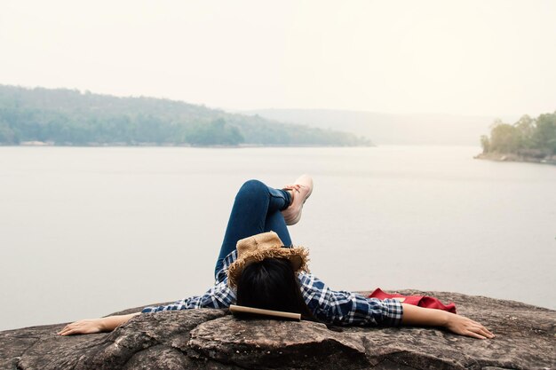 Junge Frau liegt auf einem Felsen am See vor klarem Himmel