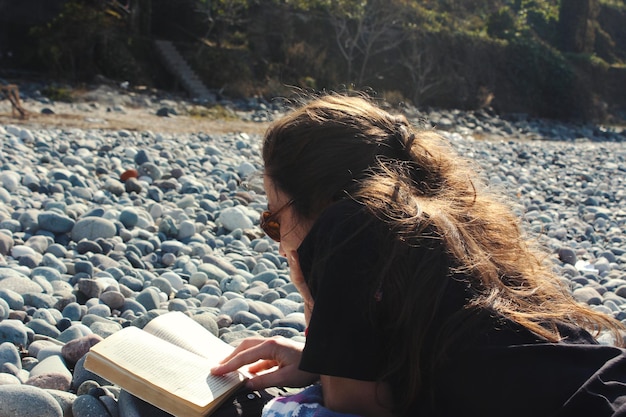 Foto junge frau liest ein buch am strand sonne und sommerferien im schwarzen meer