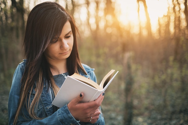 Junge Frau liest ein Buch im Wald