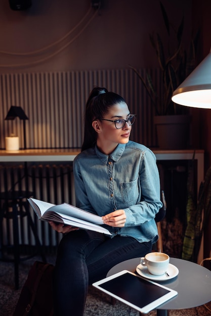 Junge Frau liest ein Buch in einem Café