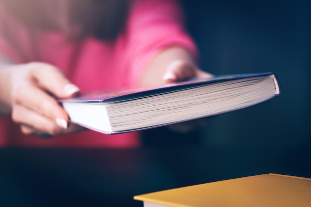 Foto junge frau liest zu hause ein buch. der hintergrund jedoch unscharf horizontal, filmeffekt.