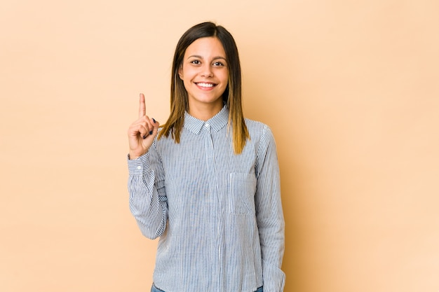 Junge Frau lokalisiert auf Beige, die Nummer eins mit Finger zeigt.