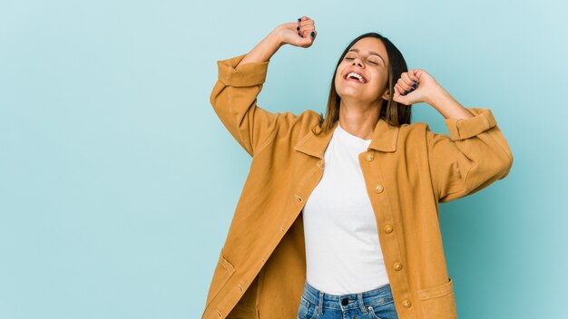 Junge Frau lokalisiert auf Blau, das einen besonderen Tag feiert, springt und Arme mit Energie hebt.