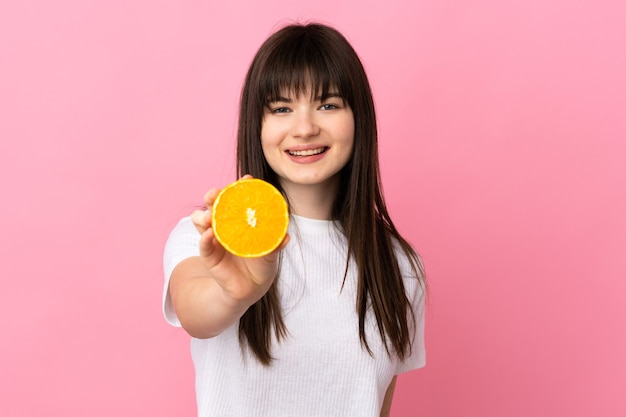 Junge Frau lokalisiert auf Rosa, die eine Orange hält